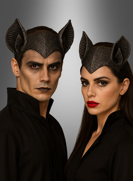 Zwei Personen in schwarzen Outfits und mit Unisex-Kopfbedeckungen mit Fledermausohren stehen vor einem grau abgestuften Hintergrund und blicken ernst in die Kamera. Das von Fledermäusen inspirierte Halloween-Accessoire verleiht ihrem dramatischen Look eine auffällige Note.