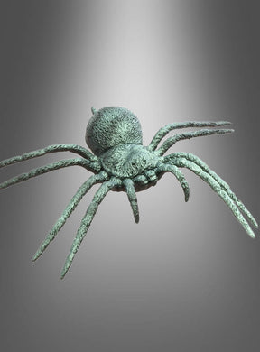 Eine realistisch gestaltete Metallspinnen-Skulptur mit dem Titel „Spinne Halloween 23 cm grün irisierend“, die acht Beine und schimmernde, grün-irisierende Akzente am Körper aufweist, wird vor einem neutralen grauen Hintergrund mit einem Spotlicht-Effekt mit Farbverlauf präsentiert – was sie zu einer auffälligen Halloween-Dekospinne macht.