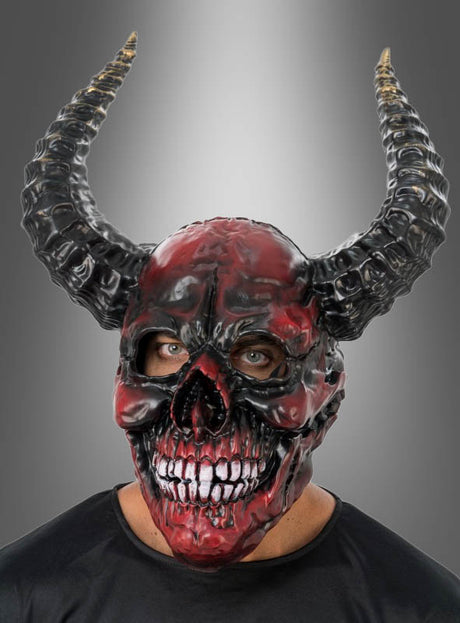 Eine Person, die die auffällige „Roter Dämon mit Hörner Maske Deluxe“ trägt – eine rot-schwarze Vollgesichts-Dämonenmaske mit großen, geschwungenen Hörnern und sichtbaren Augen –, vor einem grauen Hintergrund mit Farbverlauf. Diese dramatische Schaumstoff-Teufels-Vollmaske ist als Maske mit Hörnern konzipiert und sorgt für einen unvergesslichen Look.