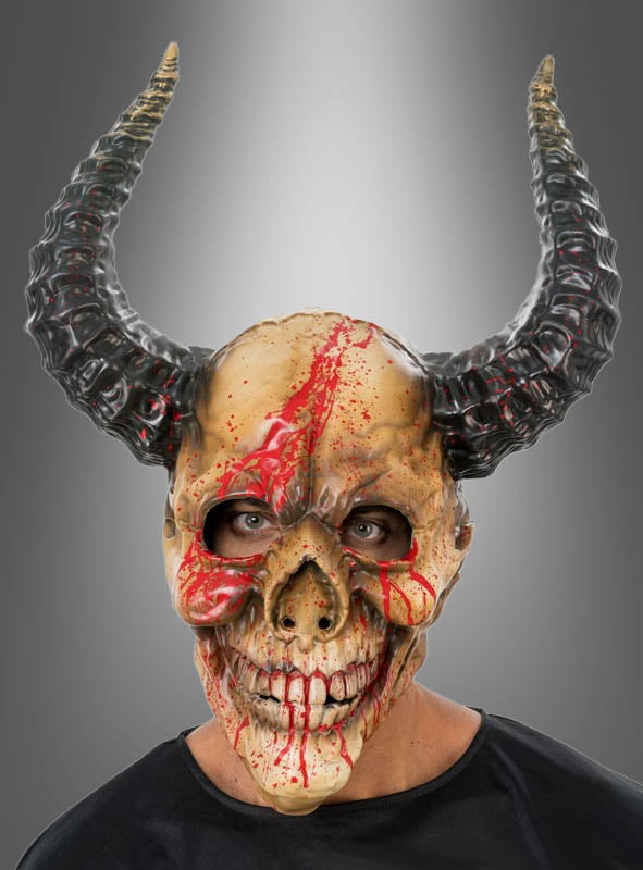 Eine Person, die die „Blutige Dämonen-Vollmaske mit Hörnern“ trägt – eine als gehörnte Totenkopfmaske mit roten, blutähnlichen Streifen gestaltete Maske – vor einem grauen Hintergrund mit Farbverlauf.
