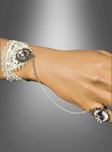 Eine Hand, geschmückt mit dem Steampunk-Handschmuck-Set mit Spitze, bestehend aus einem auffälligen Edelsteinarmband, das über eine zarte Kette mit einem passenden Edelsteinring verbunden ist, präsentiert vor einem grauen Hintergrund mit Farbverlauf – ein exquisites Accessoire, das jedes Steampunk-Outfit aufwertet oder Ihren Look abrundet.