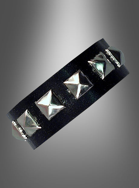 Ein schwarzes Lederarmband mit gleichmäßig verteilten silbernen Pyramidennieten, präsentiert vor einem grau verlaufenden Hintergrund – dieses Nietenarmband „Rocker Punk“ ist der perfekte 80er-Jahre-Schmuck und ein auffälliges Punk-Accessoire für jeden gewagten Look.