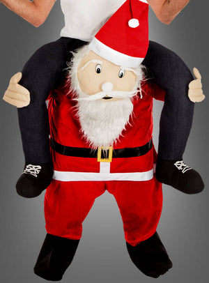 Eine Person, die ein „2. Wahl Huckepackkostüm Weihnachtsmann“ trägt – ein Kostüm im Weihnachtsmann-Stil, das den Anschein erweckt, als würde der Weihnachtsmann sie auf seinen Schultern tragen – eine auffällige Wahl, die sich perfekt für jede Weihnachtsmarkt-Verkleidung eignet.