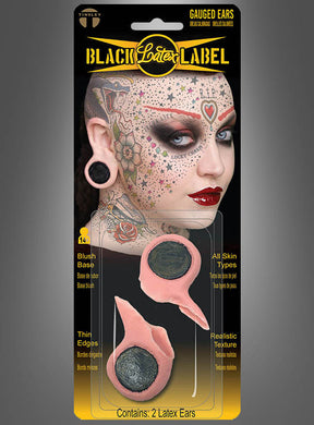 Kunststoffverpackung mit zwei „Flesh Plug Ohrläppchen Loch Tinsley Transfers“ – Latex-Ohrprothesen für gedehnte Ohrläppchen, ideal als Flesh-Tunnel-Imitate – mit einem Beispielbild eines stark tätowierten und gepiercten Models, perfekt zur Vervollständigung Ihres 90er-Jahre-Kostüms.