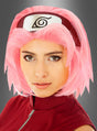 Eine Person, die eine rosa „Sakura“-Perücke für Erwachsene, ein rotes Outfit und ein Stirnband mit einem stilisierten Wirbel-Symbol trägt, posiert vor einem grauen Hintergrund mit Farbverlauf für ein beeindruckendes „Naruto Shippuden“-Cosplay.