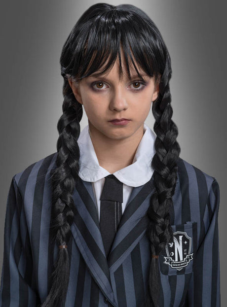 Eine Person, die die „Wednesday“-Perücke für Kinder mit langen, schwarzen Zöpfen trägt, kombiniert diese vor einem neutralen Hintergrund perfekt mit einem schwarz-grau gestreiften Blazer, einem weißen Hemd und einer schwarzen Krawatte – eine tolle Wahl für ein „Addams Family“-Kostüm.