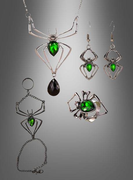 Das „Spinnen-Schmuckset mit grünem Edelstein“ besteht aus silbernen, spinnenförmigen Schmuckstücken, die in der Mitte mit grünen Edelsteinen verziert sind, darunter eine Halskette, Ohrringe, ein Armband, ein Ring und ein Schlüsselanhänger – ein auffälliges Accessoire im Gothic-Stil. Das Set wird vor einem grau verlaufenden Hintergrund präsentiert.