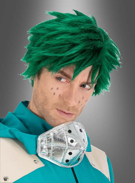 Eine Person, die die Izuku-Midoriya-Perücke aus „My Hero Academia“ für Erwachsene trägt – mit grünen, abstehenden Haaren –, dazu Gesichtsmarkierungen, ein silbermetallisches Halsaccessoire sowie ein türkis-beiges Outfit, blickt vor einem grauen Hintergrund mit Farbverlauf zur Seite.