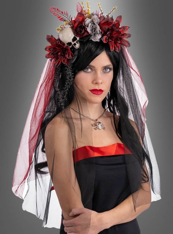 Vor einem grauen Hintergrund steht eine Frau, die ein schwarz-rotes Kleid, eine schwarze Perücke, einen dunklen Schleier und den „Totenkopf-Kopfschmuck mit Schleier“ – einen mit Blumen verzierten Totenkopf-Kopfschmuck – trägt, der an den Geist des „Tag der Toten“ erinnert.