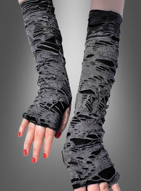 Zu sehen sind zwei Hände, die „Fetzige Zombie-Armstulpen“ tragen – lange, fingerlose Handschuhe im Used-Look in Grau, unter denen schwarzer Stoff durchscheint. Die Nägel sind in leuchtendem Rot lackiert und eignen sich perfekt für ein Halloween-Kostüm im Zombie-Stil. Der Hintergrund ist in einem neutralen Grau-Farbverlauf gehalten.