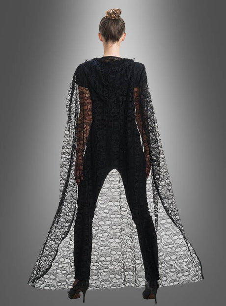 Eine Person steht mit dem Rücken zur Kamera und trägt den „Umhang aus Spitze 140 cm mit Totenköpfen“ – einen eleganten, transparenten schwarzen Umhang, der mit Totenkopfmotiven verziert ist – über einem schwarzen Outfit und High Heels, vor einem grauen Hintergrund mit Farbverlauf.