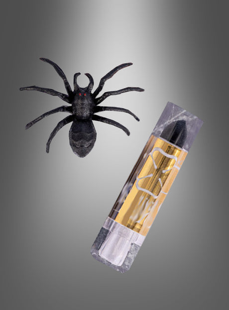 Ein schwarzer Lippenstift und ein Spinnenring sind vor einem grauen Hintergrund mit Farbverlauf zu sehen, was den geheimnisvollen Reiz von Halloween-Make-up und ein kühnes, dramatisches Statement vermittelt.