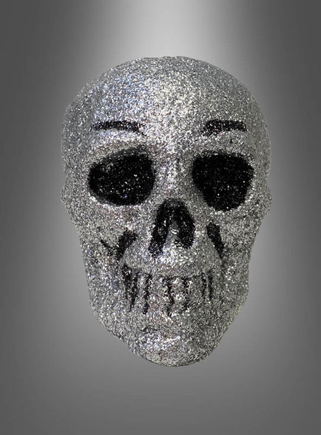 Ein glitzernder silberner Totenkopf als stilvolle Halloween-Dekoration vor einem grauen Hintergrund mit Farbverlauf.