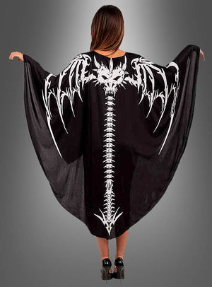 Ein Model trägt den „Drachen-Skelett-Umhang“ mit einem auffälligen Motiv aus einer weißen Fledermaus und einem Wirbelsäulen-Skelett auf dem Rücken; die Arme sind ausgestreckt, um das Design vor einem grauen Hintergrund zur Geltung zu bringen – ideal als Halloween-Kostüm oder Karnevalsumhang.