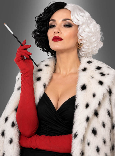 Eine Frau trägt das „Cruel Girl“-Kostümset mit schwarz-weißer Perücke, bestehend aus einer schwarz-weißen Perücke, einem Kunstpelzmantel mit schwarzen Flecken aus dem „Dalmatiner“-Accessoire-Set, langen roten Handschuhen und einem schwarzen Kleid, während sie vor einem grauen Hintergrund eine Zigarettenspitze in der Hand hält.