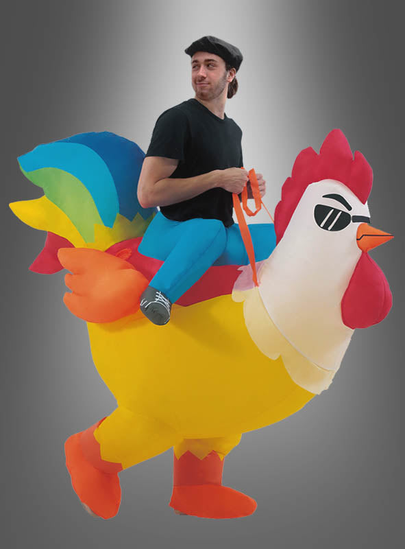 Eine Person in schwarzem T-Shirt und Baskenmütze posiert im aufblasbaren Huhn-Kostüm mit Ventilator, wodurch es so aussieht, als würde sie auf einem großen, bunten Huhn mit Sonnenbrille reiten. Dieses lustige Huhn-Kostüm ist perfekt für Erwachsene, die auf jeder Party oder Veranstaltung ein auffälliges Statement setzen möchten.