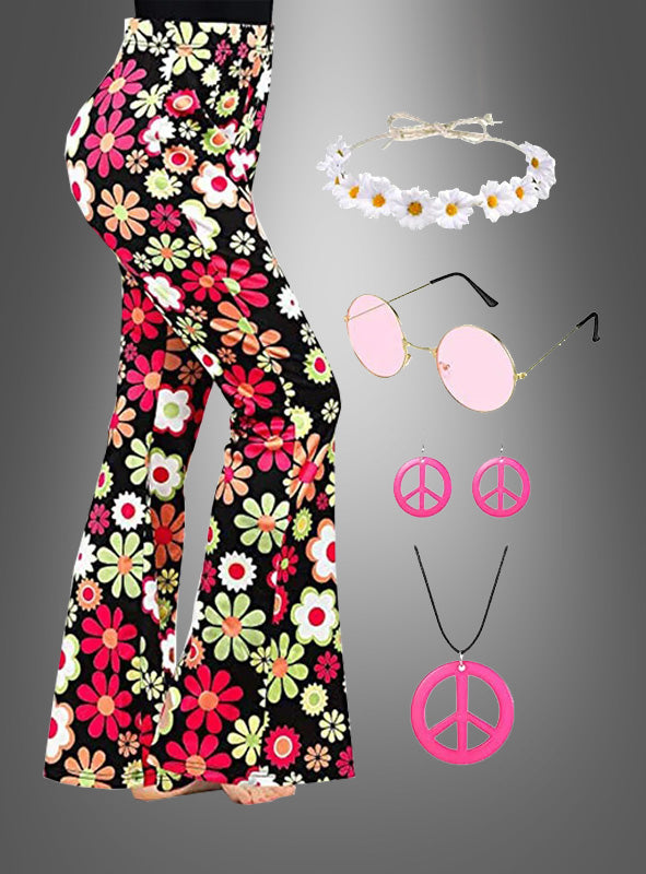 Das Outfit umfasst das „Flower Hippie Set“ mit einer rosa Schlaghose und Accessoires, darunter eine geblümte Schlaghose im Stil der 70er-Jahre, ein weißes Gänseblümchen-Stirnband, eine runde rosa Sonnenbrille, rosa Peace-Zeichen-Ohrringe und eine passende Peace-Zeichen-Halskette – perfekt, um dein Hippie-Party-Outfit abzurunden. Abgebildet vor grauem Hintergrund.