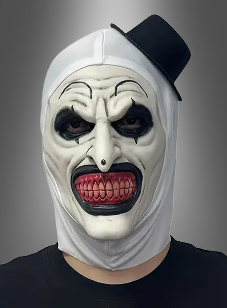 Eine Person, die die „Gruselige Clownmaske mit Zylinder“ trägt, mit übertriebener schwarz-weißer Gesichtsbemalung, spitzen Zähnen und einem kleinen, schräg sitzenden Zylinderhut, vor einem grauen Hintergrund.