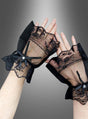 Vor einem grau verlaufenden Hintergrund sind zwei Hände zu sehen, die die „Gothic Armstulpen mit Spitze“ tragen – schwarze, fingerlose Handschuhe aus Spitze, verziert mit Schleifen und Perlenakzenten. Diese Handschuhe erinnern an elegante Spitze und verleihen jedem Steampunk-Outfit eine dramatische Note.