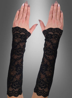 Vor einem grau verlaufenden Hintergrund sind zwei Hände zu sehen, die die „Lange Spitzen Armstulpen“ tragen – 30 cm lange, schwarze, fingerlose Handschuhe aus Blumenspitze mit gewellten Rändern. Diese schwarzen Armstulpen sind das perfekte Halloween-Kostüm-Accessoire, um Ihrem Look eine elegante und geheimnisvolle Note zu verleihen.