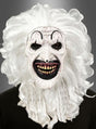 Eine Person, die die schwarz-weiße Clownmaske mit Haaren trägt – mit einem grotesken schwarz-weißen Design, einem übertrieben großen schwarzen Mund, gelben Zähnen, geschwungenen Augenbrauen, roten Flecken und langen weißen Locken –, steht vor einem grauen Hintergrund.
