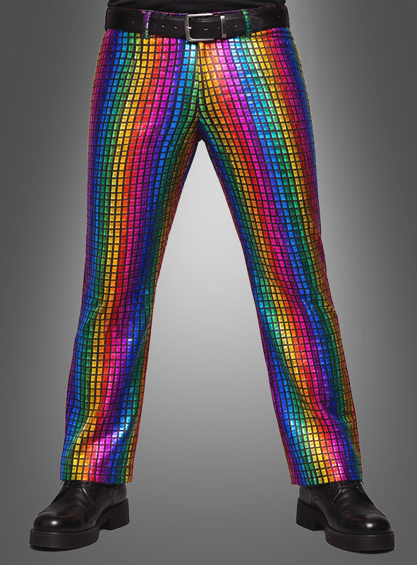 Eine Person, die schwarze Schuhe, einen schwarzen Gürtel und die „Regenbogen Hose für Herren“ trägt – eine glänzende Disco-Hose mit Pailletten und einem bunten Regenbogen-Karomuster –, steht vor einem grauen Hintergrund.