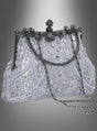 Die silberne Pailletten-Handtasche im Stil der 20er Jahre besticht durch kunstvolle silberne Pailletten, aufwendige Perlenstickerei, einen stabilen Metallrahmen, einen eleganten Verschluss mit Blumenmotiv und einen langen Kettenriemen – und verkörpert damit perfekt die Raffinesse des Stils der 1920er Jahre. Diese exquisite Handtasche wird vor einem grau verlaufenden Hintergrund präsentiert.