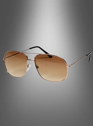 Die braune Retro-Sonnenbrille im 70er-Jahre-Stil präsentiert sich mit einem goldfarbenen Aviator-Rahmen, braun verlaufenden Gläsern und schwarz abgesetzten Bügelenden in einem eleganten 70er-Jahre-Stil als moderne Interpretation der klassischen Retro-Sonnenbrille – stilvoll in Szene gesetzt vor grauem Hintergrund.