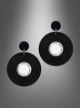 Ein Paar „80er“-Ohrringe im Schallplatten-Design in Schwarz-Weiß: schwarze, runde Ohrringe mit weißen Mittelstücken, die an Schallplatten erinnern, präsentiert vor einem grauen Hintergrund mit Farbverlauf.