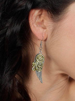Eine Nahaufnahme des Ohrs einer Person, die die „Ohrringe Steampunk Schwingen“ trägt – silberne und goldene Ohrringe in Eulenform mit aufwendig gearbeiteten Zahnrad- und Flügeldetails –, unterstreicht deren einzigartigen Charme und verleiht Ihrem Look einen Hauch von Vintage-Flair.