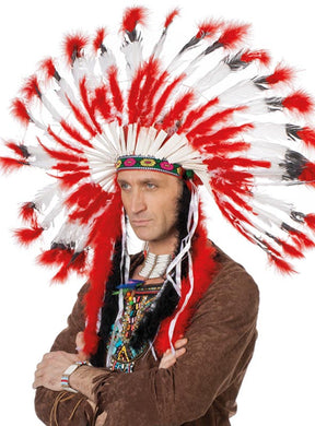 Eine Person, die den „Indianer Häuptling Kopfschmuck Deluxe rot-weiß“ – einen großen Kopfschmuck mit roten und weißen Federn – sowie ein braunes Häuptling-Kostüm trägt, steht mit verschränkten Armen vor einem einfarbigen Hintergrund.