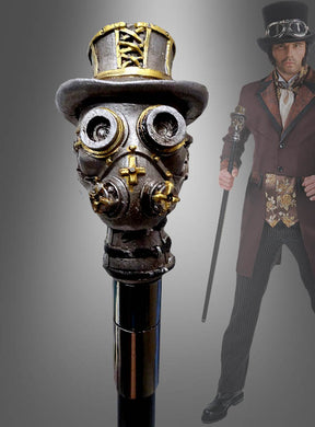 Im Hintergrund hält eine Person in einem Steampunk-Kostüm den „Deluxe Gehstock Steampunk“ – einen im Steampunk-Stil gestalteten Spazierstock mit einem Griff in Form einer Gasmaske, die einen Zylinder trägt – als auffälliges Kostümzubehör in der Hand.