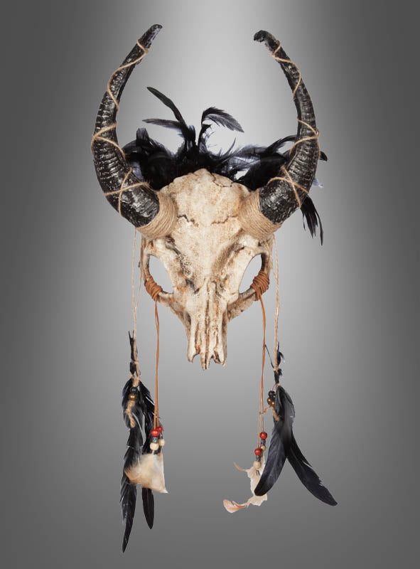 Die „Stier-Skelett-Maske mit Hörnern“, verziert mit schwarzen Federn, Seilen, Perlen und weiteren Federn, die an beiden Seiten herabhängen, wird vor einem grauen Hintergrund mit Farbverlauf präsentiert.
