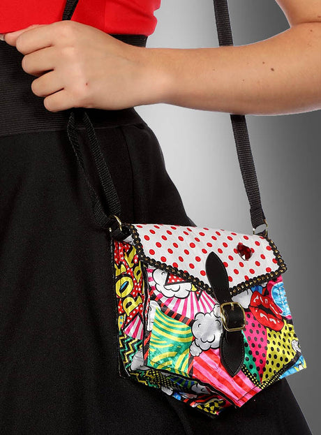 Eine Person, die einen schwarzen Rock trägt, hält die Handtasche „Comic Handtasche Pop Art“ in der Hand, die sich durch eine Klappe mit Polka-Dots und lebhafte grafische Drucke im farbenfrohen Pop-Art-Stil auszeichnet.