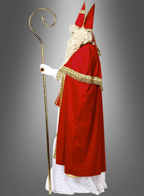 Gekleidet in das prächtige rot-weiße *Luxus-Nikolauskostüm aus Plüsch* und mit einem goldenen Stab in der Hand steht eine Person im Profil vor einem grauen Hintergrund und verkörpert damit perfekt das klassische Erscheinungsbild des Heiligen Nikolaus.