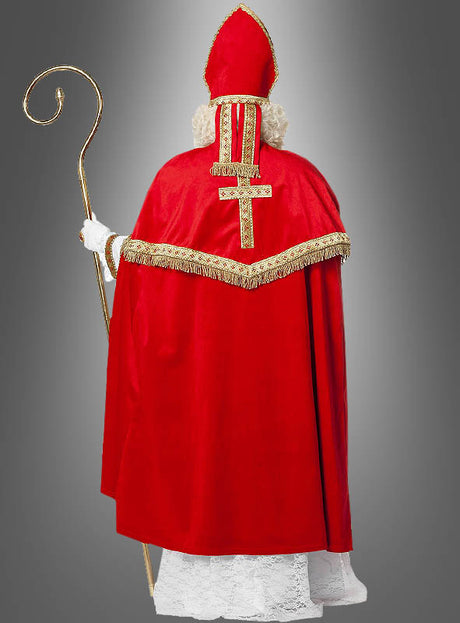 Diese Person, die von hinten vor einem grauen Hintergrund fotografiert wurde, trägt das „Luxus-Nikolaus-Kostüm aus Plüsch“ mit einem roten Umhang mit goldener Borte und einer hohen roten Mütze und hält einen goldenen Stab in der Hand.