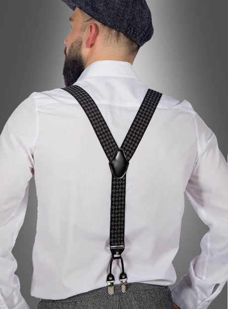 Ein Mann, der von hinten zu sehen ist und ein weißes Hemd, eine graue Hose sowie eine graue Schirmmütze trägt, präsentiert die „Deluxe 20er Hosenträger Geschenkbox Doppelclips“ mit ihren Hosenträgern im Vintage-Muster. Er steht vor einem grauen Hintergrund mit Farbverlauf und sorgt so für einen authentischen Look der 20er Jahre.