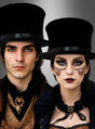 Zwei Personen, die schwarze „Klappzylinder Chapeau Claque Deluxe“-Zylinder und viktorianisch inspirierte Kleidung tragen, mit dramatischem Make-up und ausdruckslosen Gesichtern, stehen vor einem schlichten Hintergrund mit Farbverlauf.