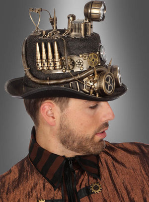 Ein Mann in einer braun gestreiften Jacke und einem schwarzen Steampunk-Zylinder mit Grubenlampe – verziert mit Zahnrädern, Rohren, Kugeln und mechanischen Teilen, die an einen klassischen Steampunk-Hut erinnern, und mit der markanten Ergänzung einer Grubenlampe – vor einem grauen Hintergrund.