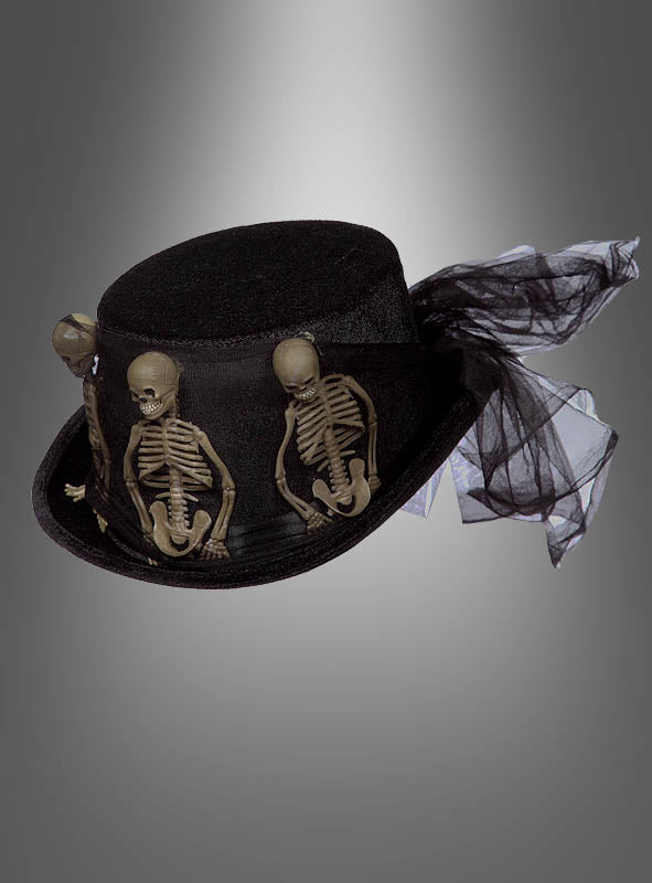 Wir präsentieren den „Gothic Samt Zylinder mit Skeletten Deluxe“: einen schwarzen Samtzylinder, der elegant mit drei kleinen Plastikskeletten und einem Hauch von dramatischem schwarzem Tüll verziert ist und vor einem grauen Hintergrund mit Farbverlauf präsentiert wird – perfekt, um Ihrem Halloween-Outfit einen gruseligen Touch zu verleihen.