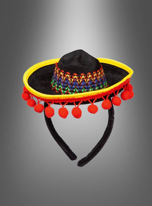 Mini-Sombrero für eine Mexikanerin – ein kleiner schwarzer Sombrero, verziert mit gelber Borte, roten Pompons und einem bunt gewebten Band – das ideale Accessoire für ein Mexikanerin-Kostüm, präsentiert vor einem grauen Farbverlauf.