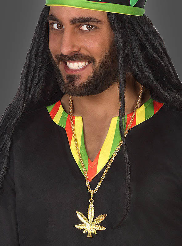 Ein Mann in klassischer Rasta-Kleidung – einem schwarzen Hemd mit roten, gelben und grünen Verzierungen, einem passenden Hut und einer goldenen Cannabis-Kette aus Metall mit einem Blatt-Anhänger – lächelt in die Kamera.