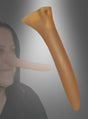 Eine Person, die die „Sehr lange Pinocchio-Nase 7 cm“ trägt, ist neben einem vergrößerten Modell einer ähnlichen Nase vor einem grauen Hintergrund mit Farbverlauf abgebildet – das perfekte Kostümzubehör für Ihre nächste Mottoparty.