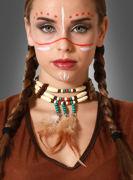 Mit einem Western-Indianer-Halsband aus Perlen mit Federakzenten, geflochtenen Haaren, Gesichtsbemalung und einem braunen Oberteil posiert diese Person vor einem grauen Hintergrund – perfekt, um jeder Wild-West-Mottoparty mit diesem auffälligen Stück Indianer-Schmuck authentisches Flair zu verleihen.