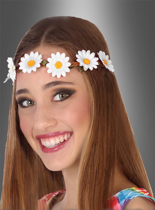 Eine lächelnde junge Frau mit langen braunen Haaren trägt ein Hippie-Blumenhaarband aus weißen Gänseblümchen vor einem grauen Hintergrund mit Farbverlauf.