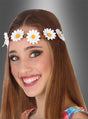 Eine lächelnde junge Frau mit langen braunen Haaren trägt ein Hippie-Blumenhaarband aus weißen Gänseblümchen vor einem grauen Hintergrund mit Farbverlauf.