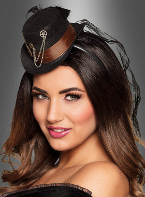Eine Frau trägt den „Zahnrad Minizylinder Steampunk“ – einen schwarzen Miniaturhut mit braunem Band, goldener Kette und Zahnradverzierungen – ein elegantes Damenaccessoire, das sich ideal für jedes Steampunk-Kostüm eignet, vor einem grauen Hintergrund mit Farbverlauf.