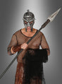 Person in Gladiatoren-Kostüm mit Helm und Netzhemd, die einen 150 cm langen Wurfspieß für Erwachsene und ein Netz in der Hand hält und vor einem grauen Hintergrund mit Farbverlauf steht.