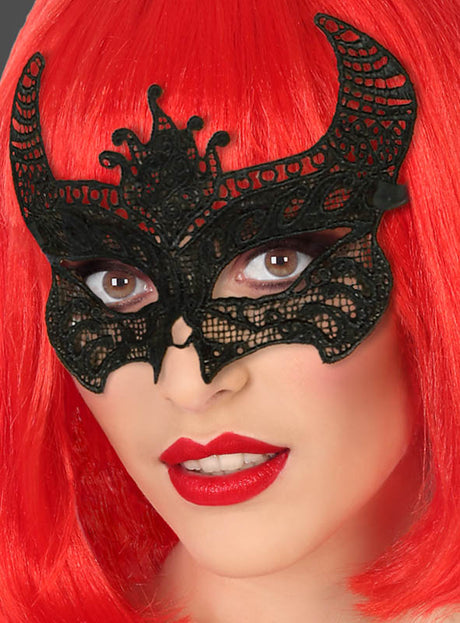 Eine Person mit leuchtend roten Haaren und rotem Lippenstift trägt die „Schwarze Teufelsmaske aus Spitze“ – eine schwarze Spitzenmaske mit Hörnern – über den Augen, was sie perfekt für ein dramatisches Gothic-Kostüm macht.