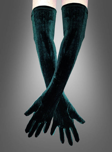 Ein Paar verschränkte Arme, die elegante Handschuhe tragen, genauer gesagt die „Grünen Samthandschuhe“ mit einer Länge von 50 cm, vor einem grauen Hintergrund mit Farbverlauf.